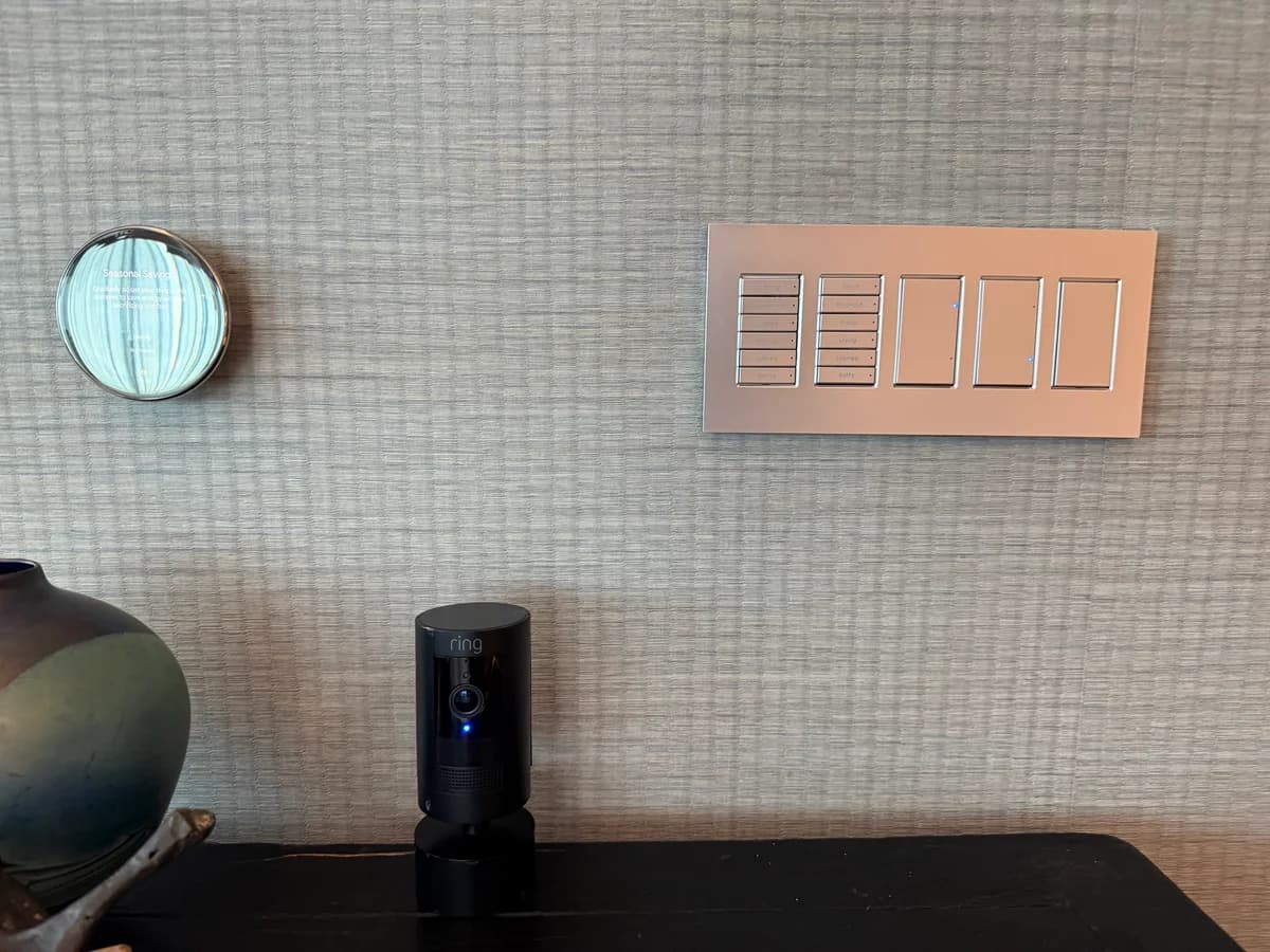 Smart home wall integration showing Nest thermostat, engraved scene keypad, and Ring security camera