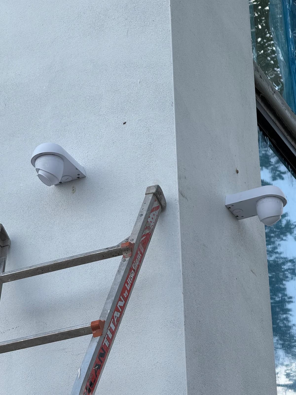 Two shrouded dome security cameras mounted on a building corner for full perimeter coverage