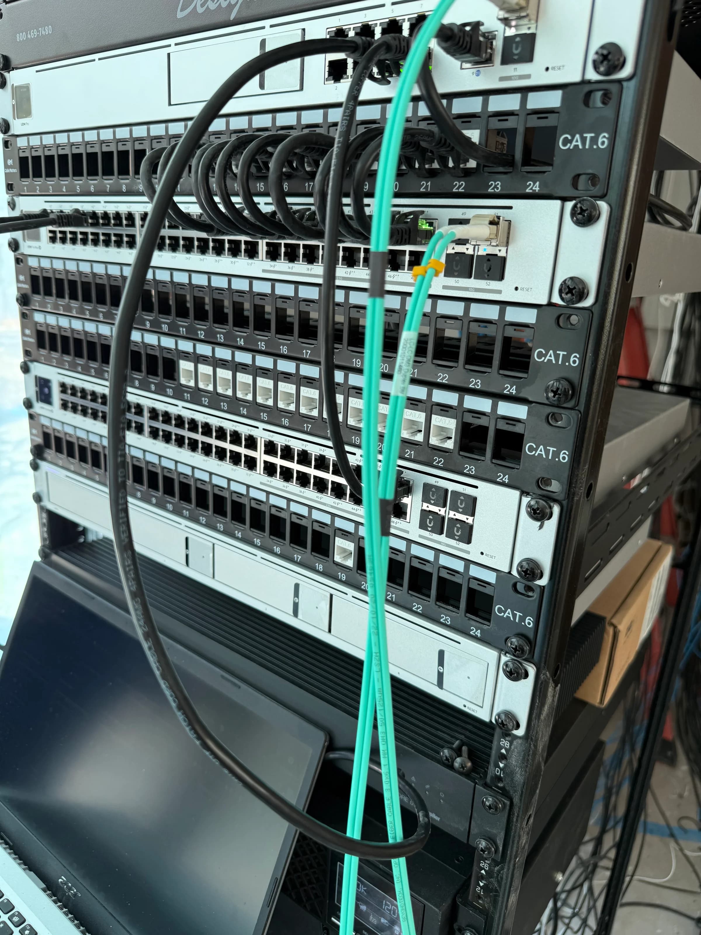 Tight close-up of CAT.6 patch panels with fiber jumpers in network rack