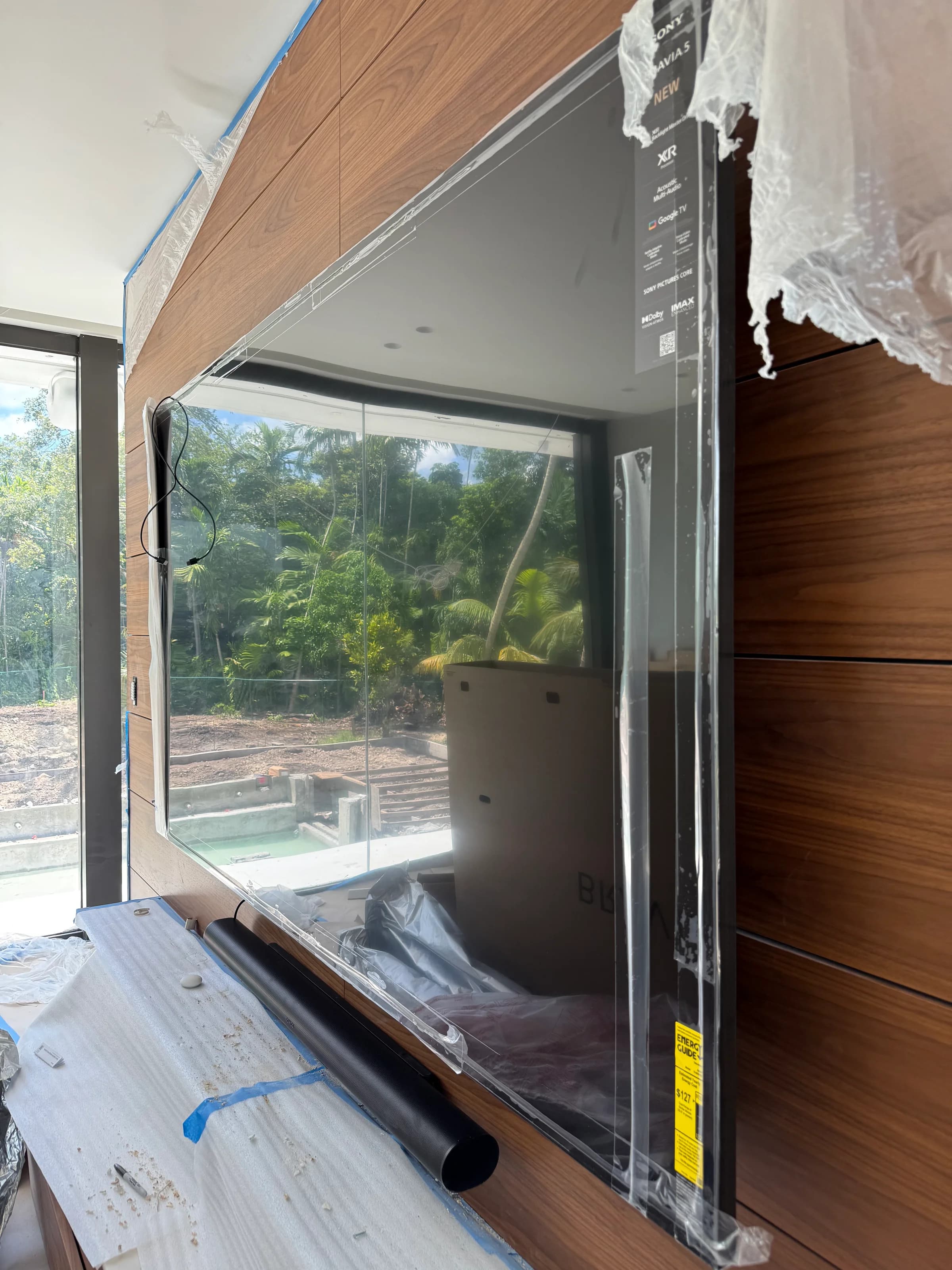 Sony Bravia television wall-mounted on custom walnut wall with protective film during installation